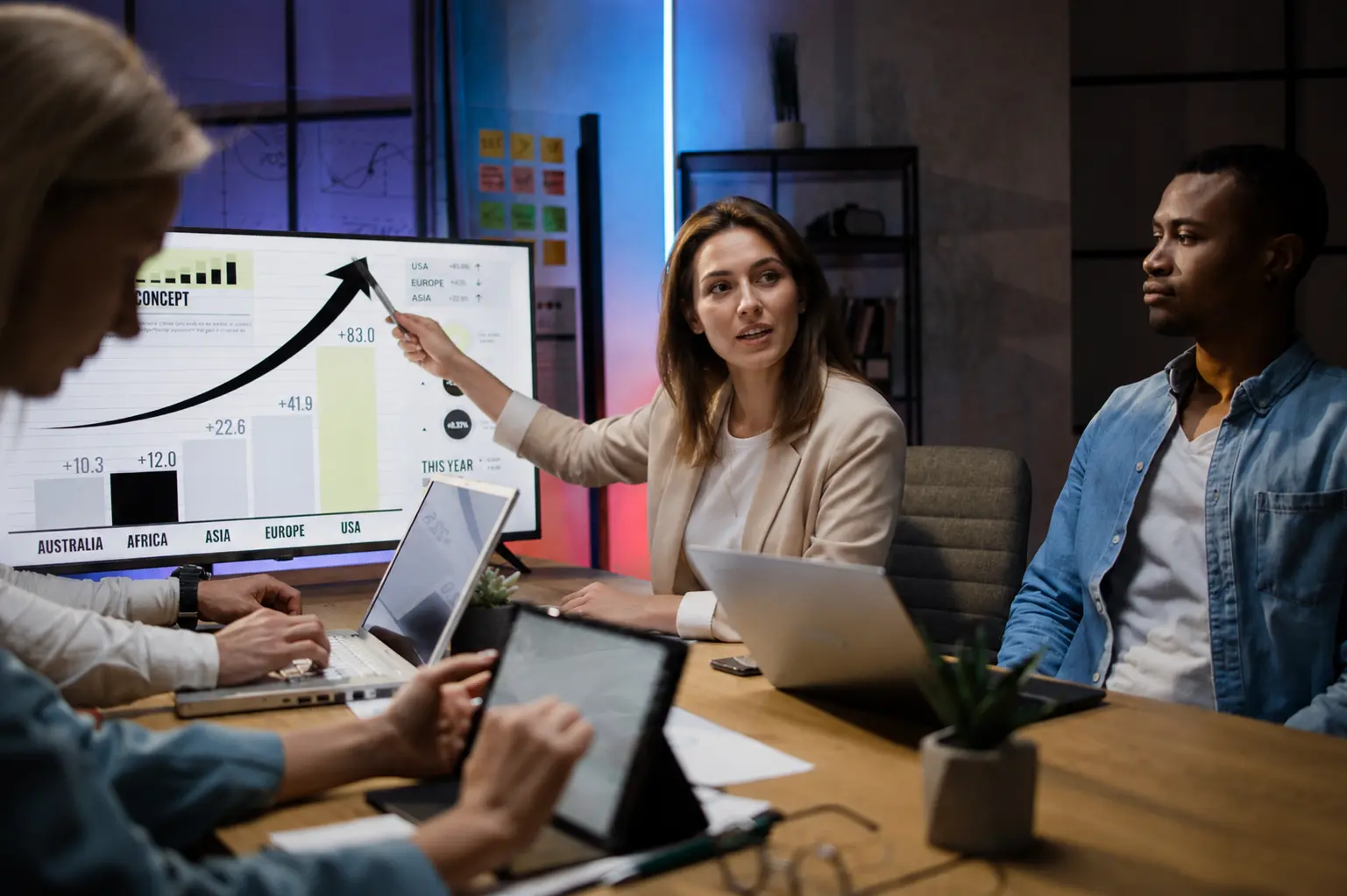 Businesswoman presenting growth analytics to colleagues in an office meeting.