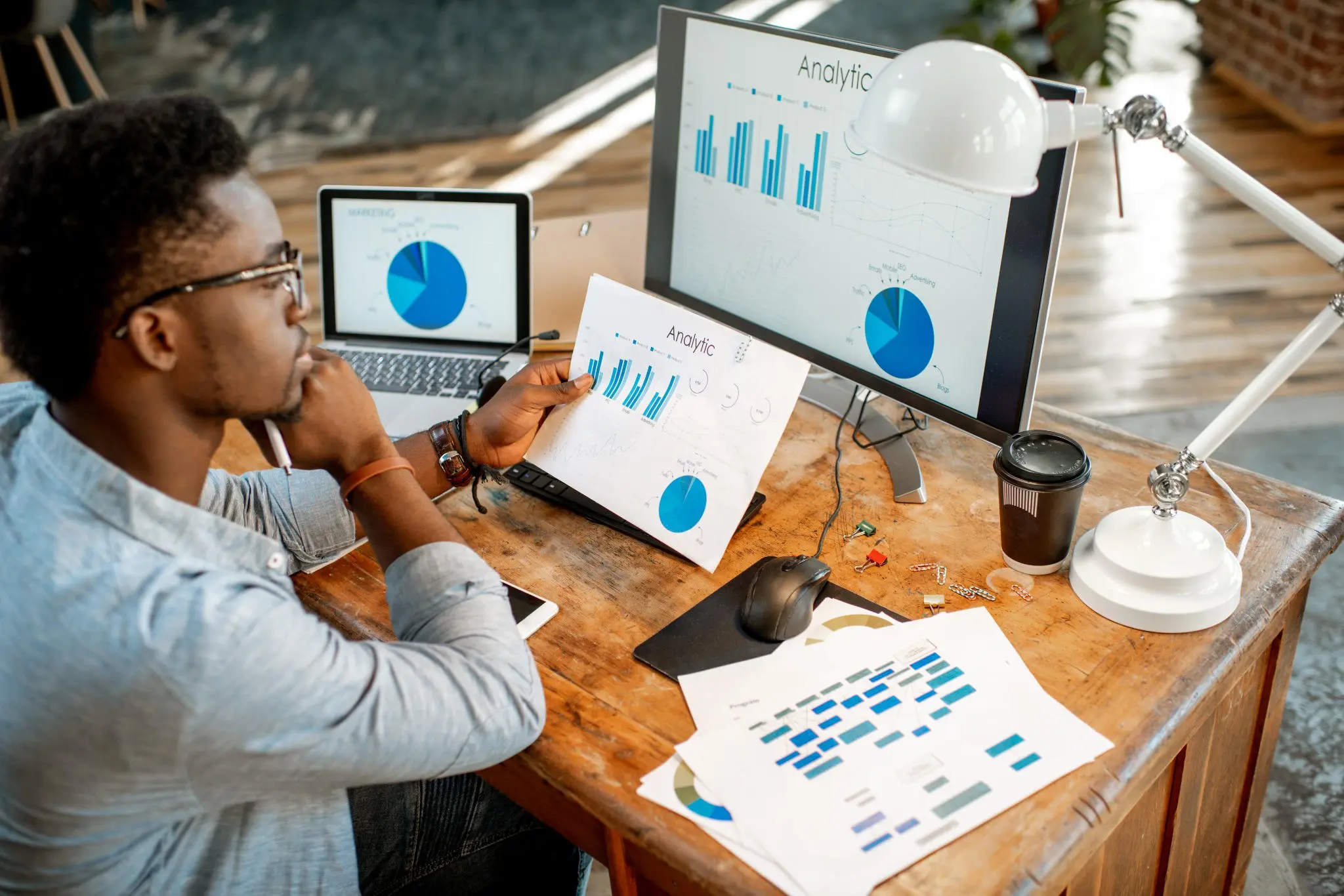 Business professional reviewing analytics charts on computer screens and reports